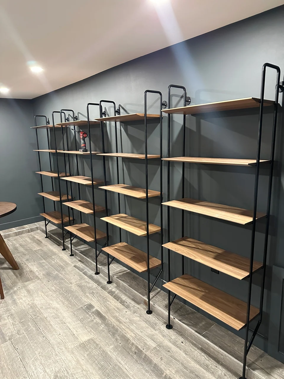 Large wall of open shelving with wood shelves and black metal uprights