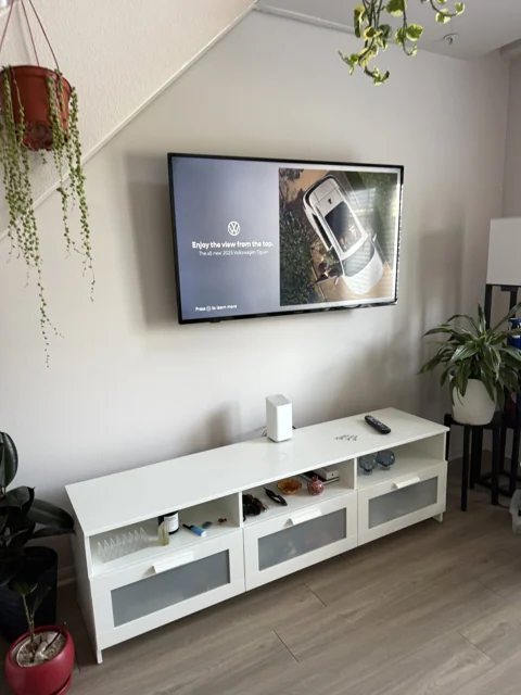 Wall-mounted television above a white console in a bright living room
