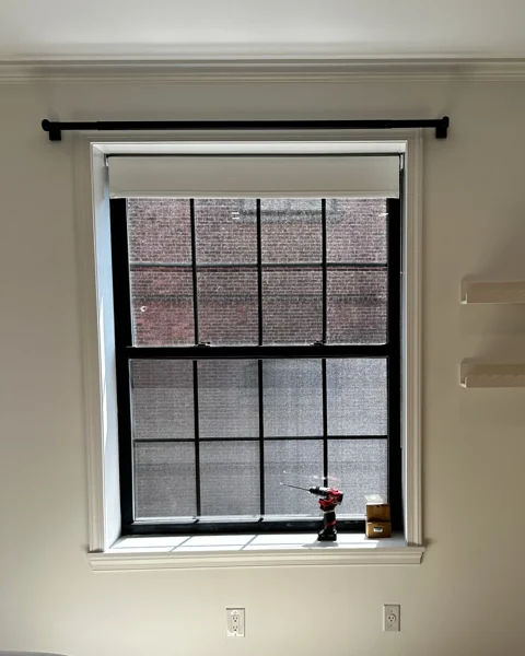 Roller blind installed above a window in a bright room