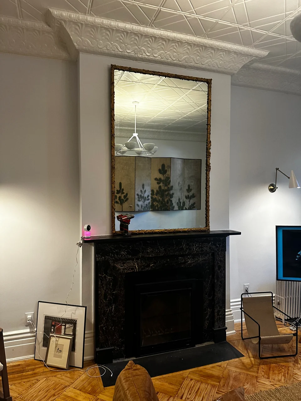 Tall framed mirror mounted above a fireplace