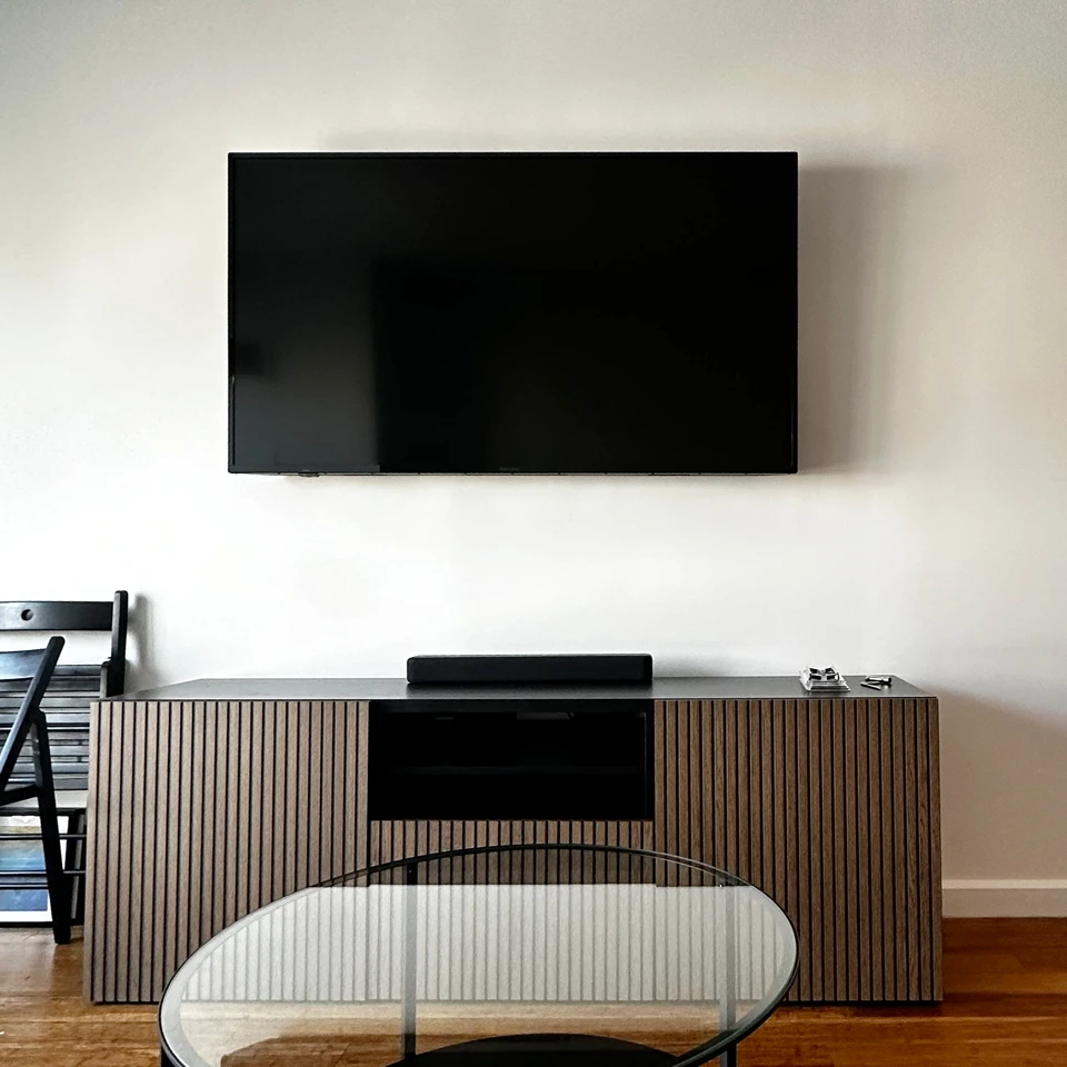 Large television mounted above a wood media console